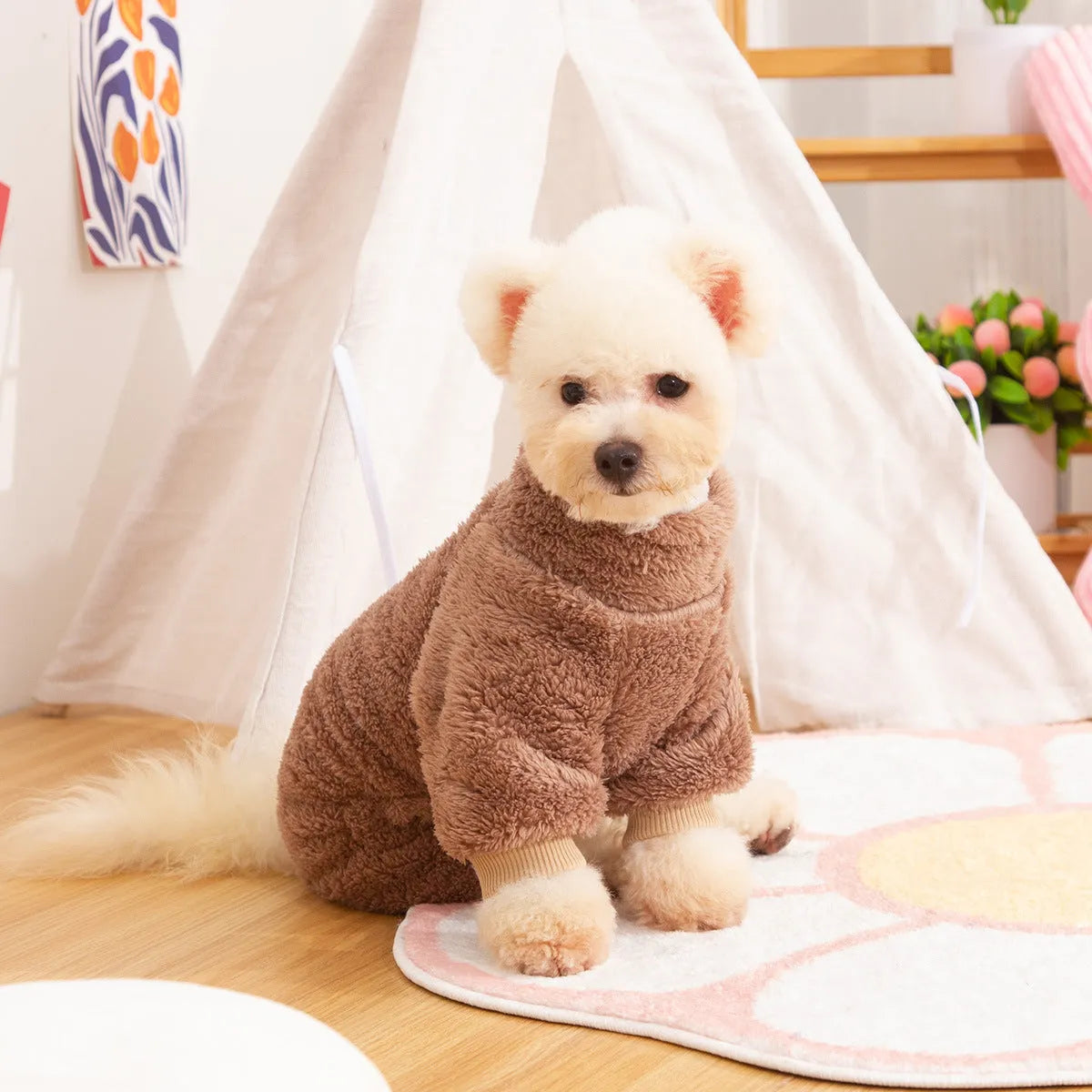 A dog wearing a blue four-legged plush jacket with a high collar and a tow ring on the back.