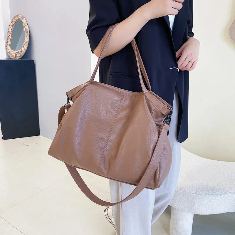 Large soft PU leather messenger bag with adjustable strap in black, shown open with internal pockets.