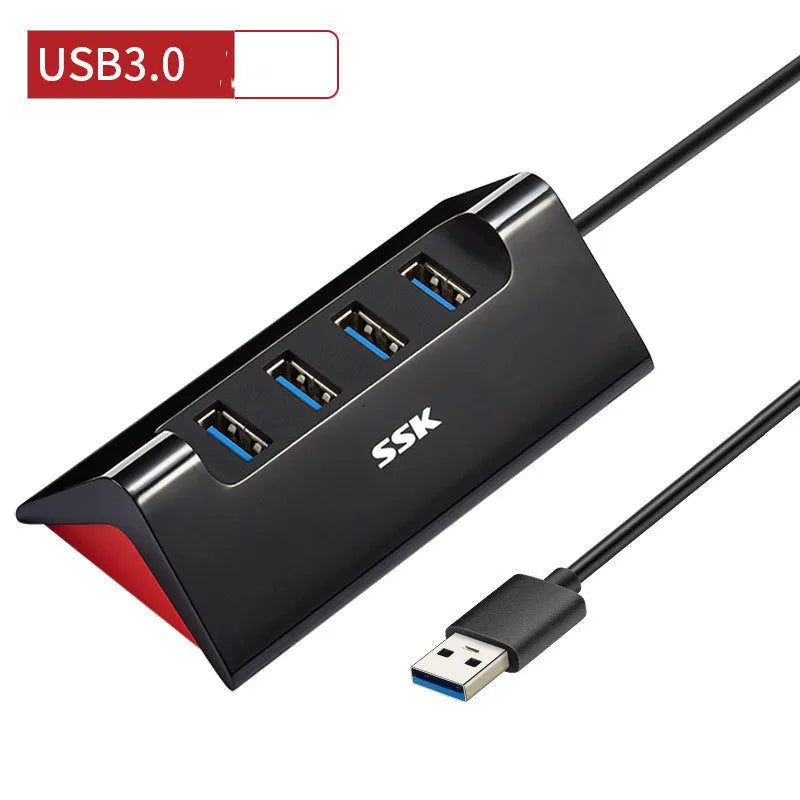 Black USB expansion dock with four ports on a desktop next to a laptop.