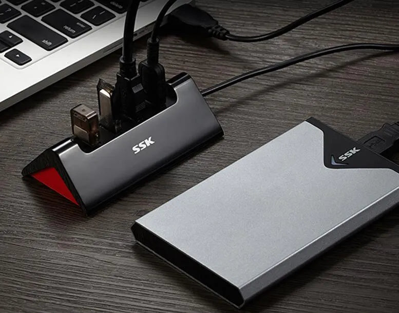 Black USB expansion dock with four ports on a desktop next to a laptop.