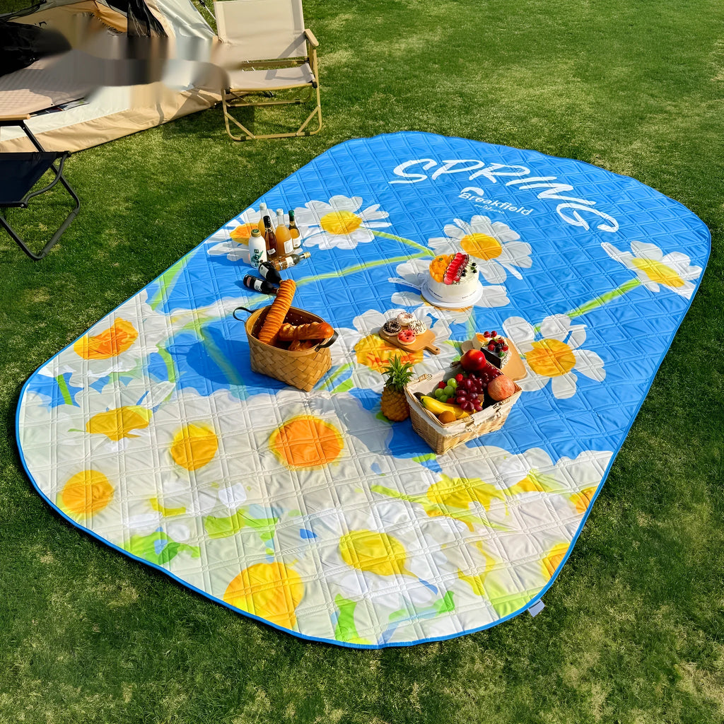 Large rectangular waterproof picnic mat with a brushed fabric texture, shown folded and in use outdoors.
