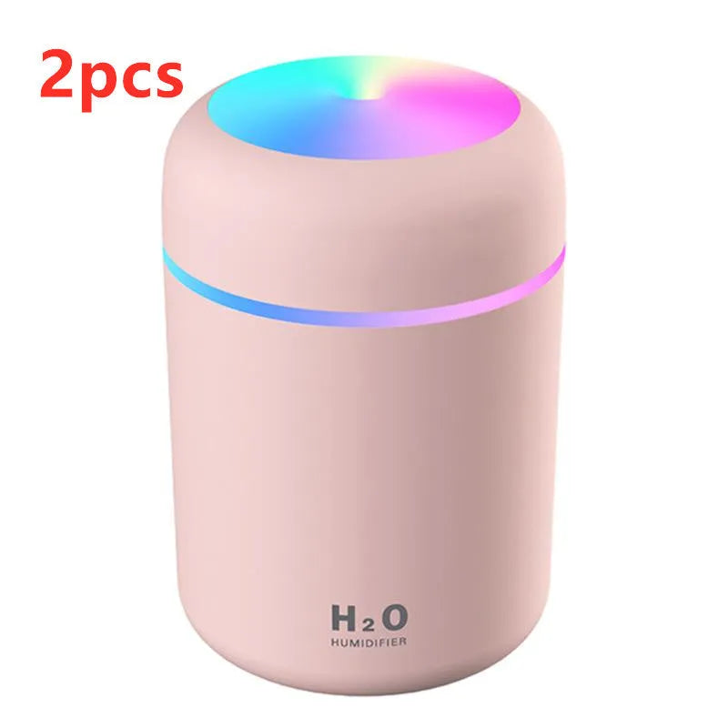 Pink USB desktop humidifier with coloured lights and water tank on a wooden desk