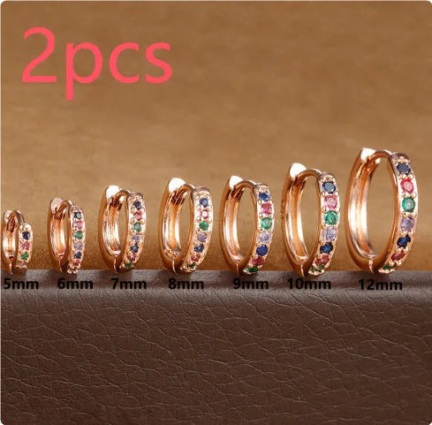 Perforated circle stud earrings with zircon detail in gold, rose gold, and silver colours on a white background.