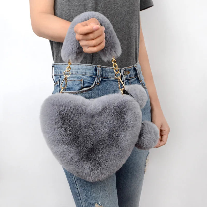 Soft plush women's handbag in a red heart shape with a zipper and detachable strap.