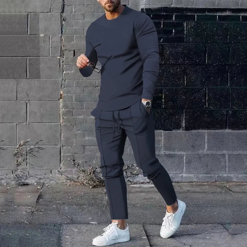 Man wearing a light grey round-neck long-sleeve t-shirt and matching trousers from a two-piece polyester suit set.