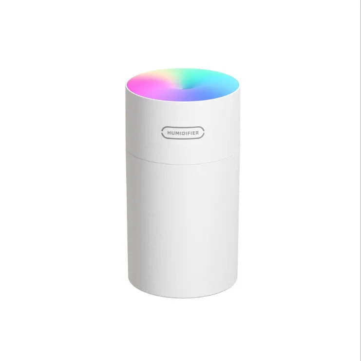 Pink USB desktop humidifier with coloured lights and water tank on a wooden desk