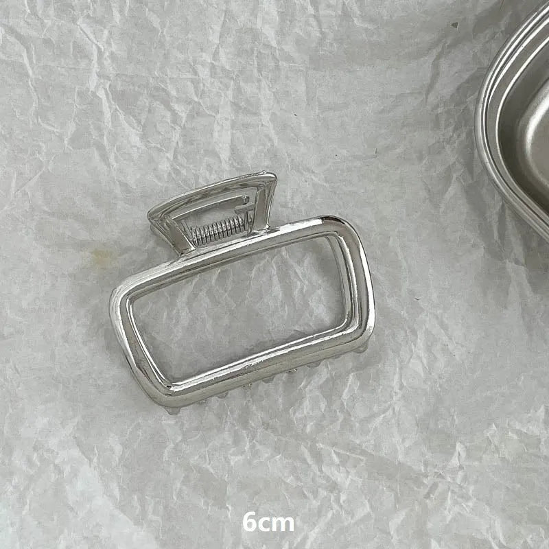 Assortment of silver metal hair claw barrettes with various designs including bows, pearls, and geometric shapes.