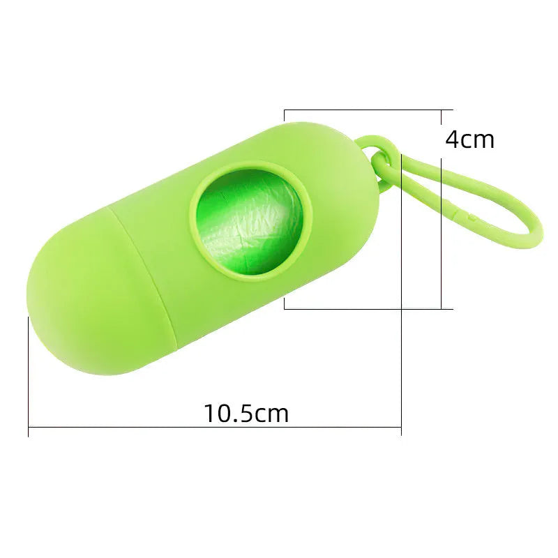 Compact black dog poop bag holder with Velcro strap and metal side hook, shown next to a roll of waste bags.