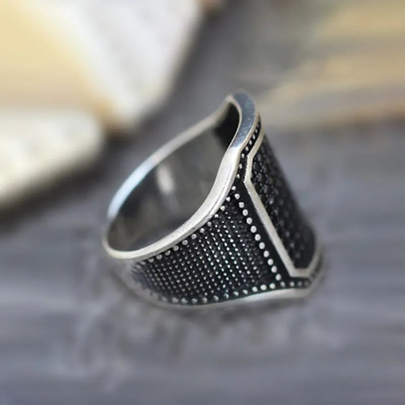 Black alloy ring with copper inlay and zircon detail on a finger, showing unisex design.
