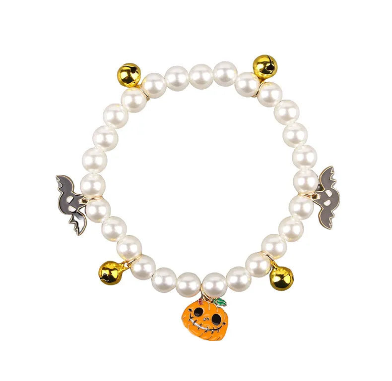 Close-up of a simulated pearl cat collar with a detailed Halloween pumpkin charm, showing the purple ghost design variant.
