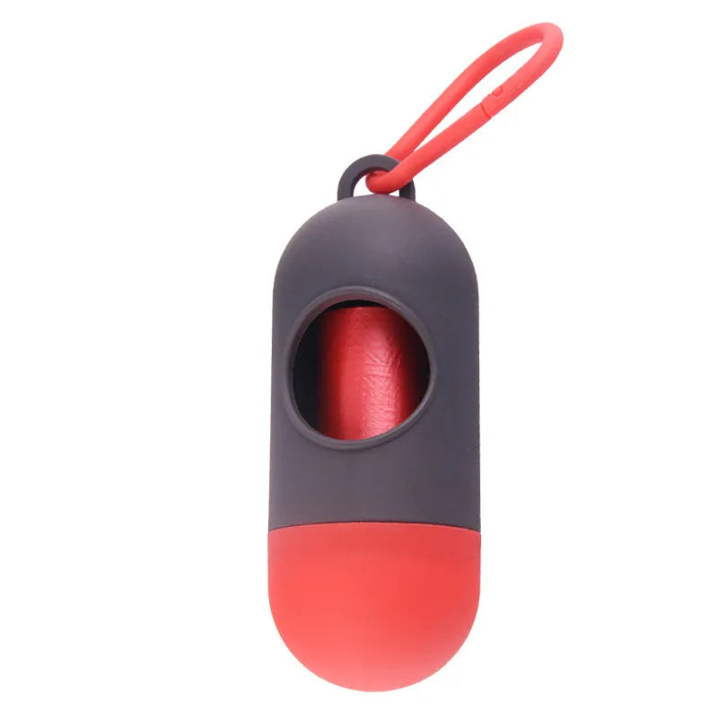 Compact black dog poop bag holder with Velcro strap and metal side hook, shown next to a roll of waste bags.