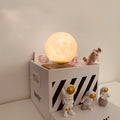Maglev floating moon and earth night light with LED glow and small astronaut figurines on a table.