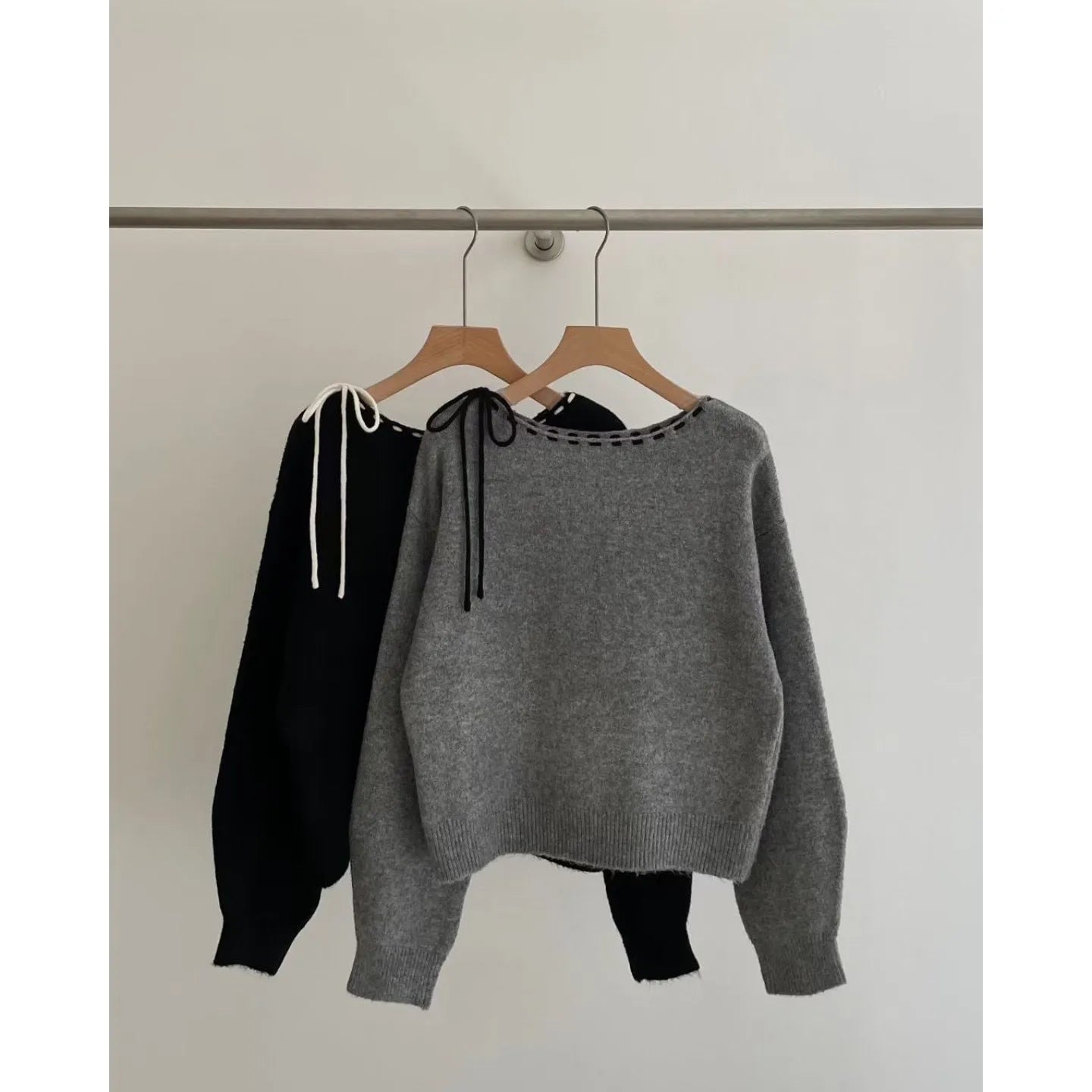 A grey women's loose-fitting long-sleeve knitwear pullover top on a hanger.