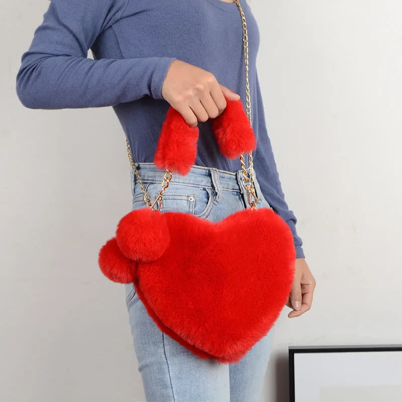 Soft plush women's handbag in a red heart shape with a zipper and detachable strap.