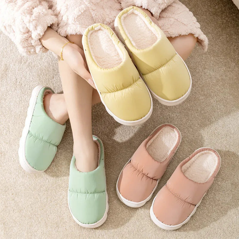 Blue down cotton indoor slippers with thick rubber sole and plush lining, shown on a wooden floor.