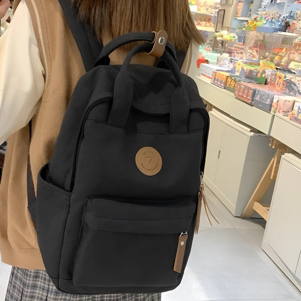 Black Oxford cloth unisex backpack with curved shoulder straps and retro sewing thread detailing