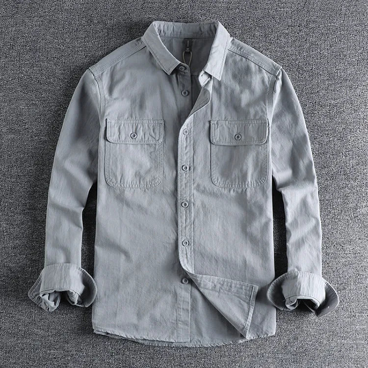 Man wearing a loose grey cardigan-style button-up shirt with long sleeves.