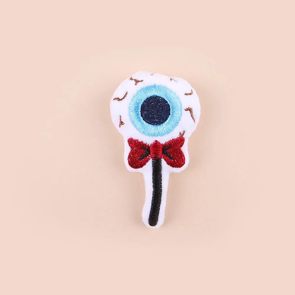 Small plush cat teaser toy with candy, eyes and skull attachments on lightweight handle
