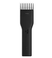 Black and white cordless electric hair clippers with adjustable comb on a stand