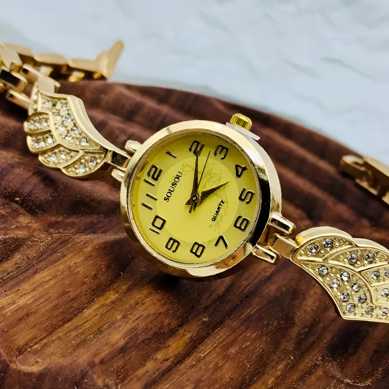 Stainless steel women's watch with round dial on wrist, showing gold surface finish option.