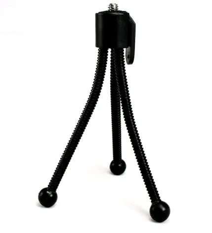 Small silver aluminium desktop tripod with ball head, shown collapsed next to an Apple iPhone for scale