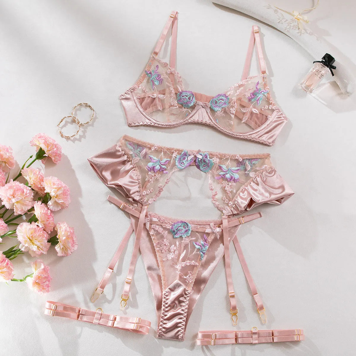 Light purple satin four-piece lingerie set laid flat, showing the three-point style and delicate fabric texture.