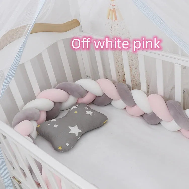 Braided knot style baby crib bumper in a light grey colour, shown lined inside a white wooden cot.