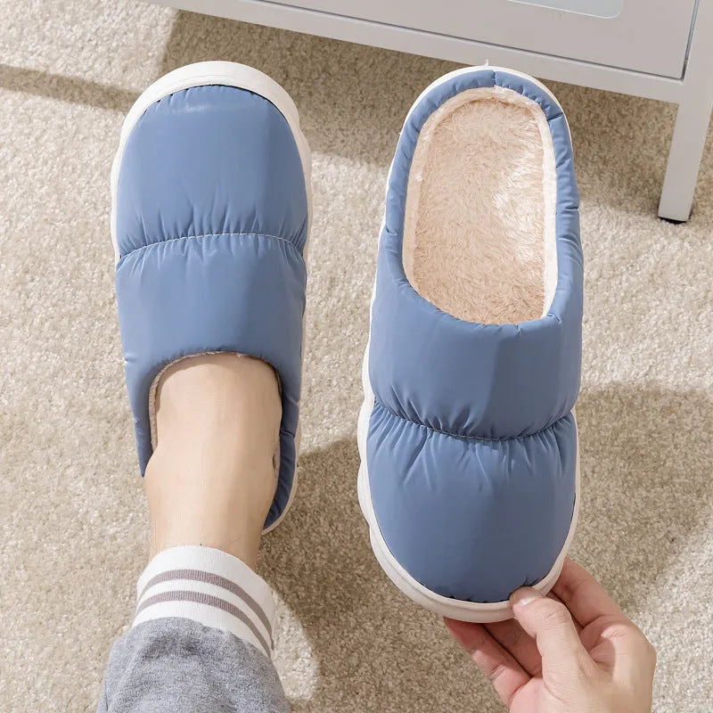 Blue down cotton indoor slippers with thick rubber sole and plush lining, shown on a wooden floor.