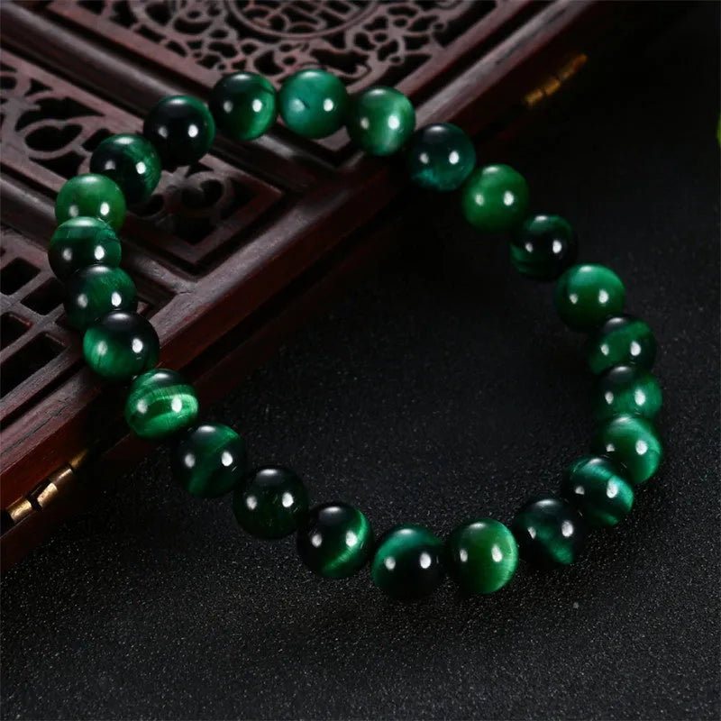 Polished green tiger eye stone bead bracelet on a wrist, showing geometric bead shapes.