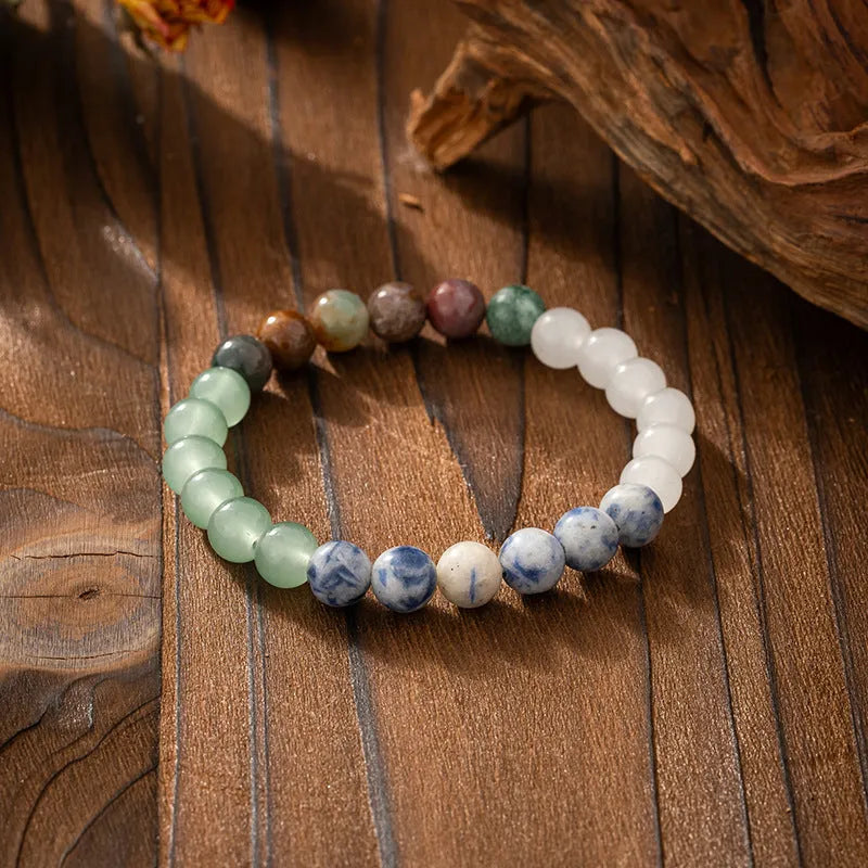 Long natural stone beaded sweater chain necklace and matching bracelet in bohemian style on a grey background.