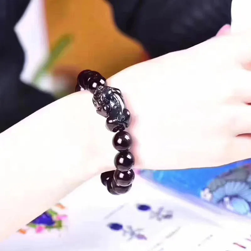 Natural ice colour eye obsidian crystal bracelet on a wrist, showing detail of the stone beads.