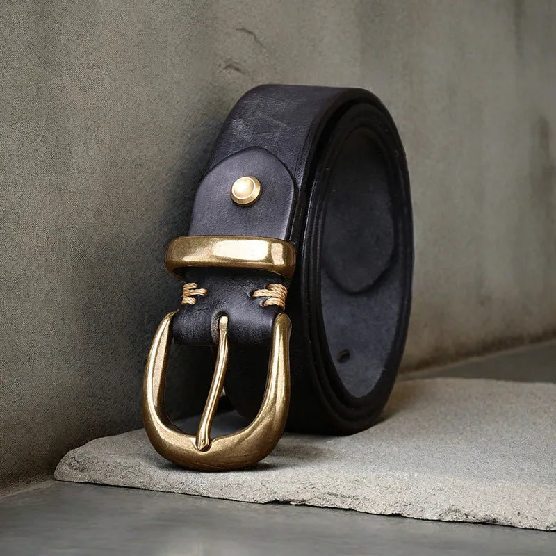 Men's black genuine cowhide leather belt with copper pin buckle on a jeans background.