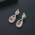 Drop shape copper earrings with inlaid synthetic gemstone in blue colour option on a white background