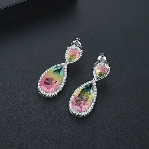 Drop shape copper earrings with inlaid synthetic gemstone in blue colour option on a white background