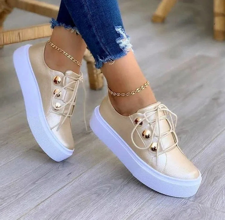 Women's white lace-up flat sneakers with silver rivet details on the sides and a round toe.