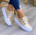 Women's white lace-up flat sneakers with silver rivet details on the sides and a round toe.
