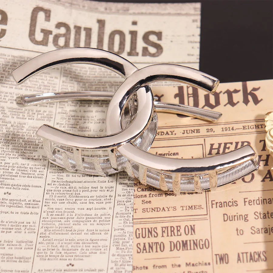 Assortment of silver metal hair claw barrettes with various designs including bows, pearls, and geometric shapes.