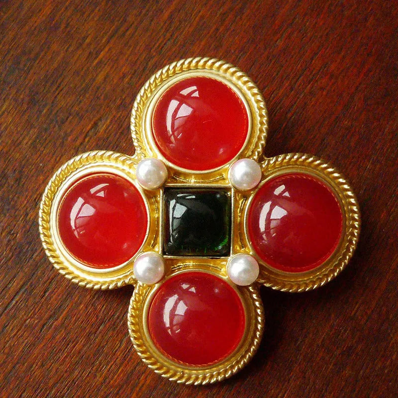 Close-up of a vintage baroque style zinc alloy brooch with a diamond shape on a dark fabric background.