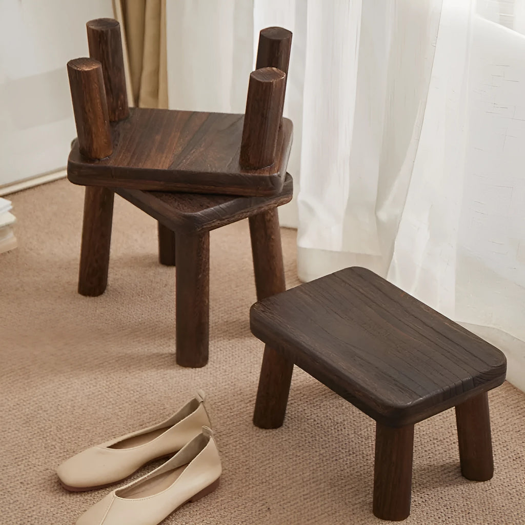 Distressed solid wood shoe changing stool with bracket structure, shown in a hallway setting.