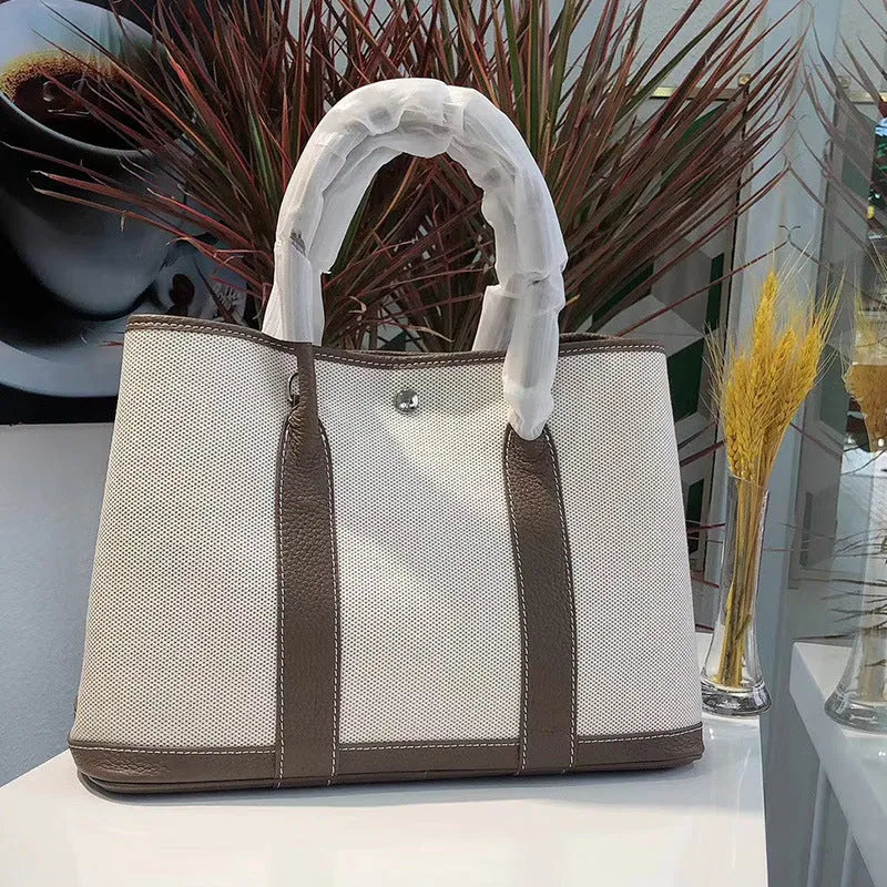 Women's canvas and leather crossbody tote bag in bucket shape with soft handles and internal zip compartments