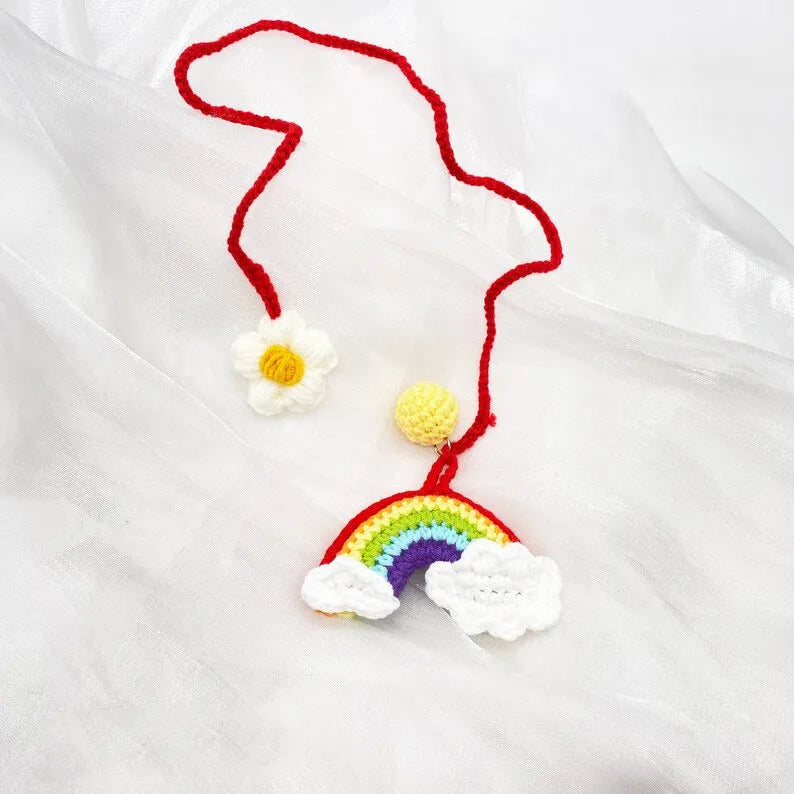 Handmade crocheted avocado flower car pendant in wool with rainbow colours hanging in vehicle