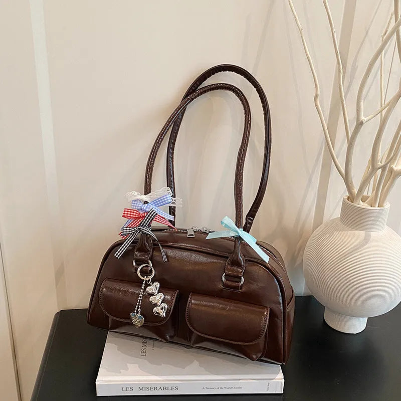 Retro women's black PU leather pillow-shaped shoulder bag with flap and double straps, shown with optional ribbon pendant.