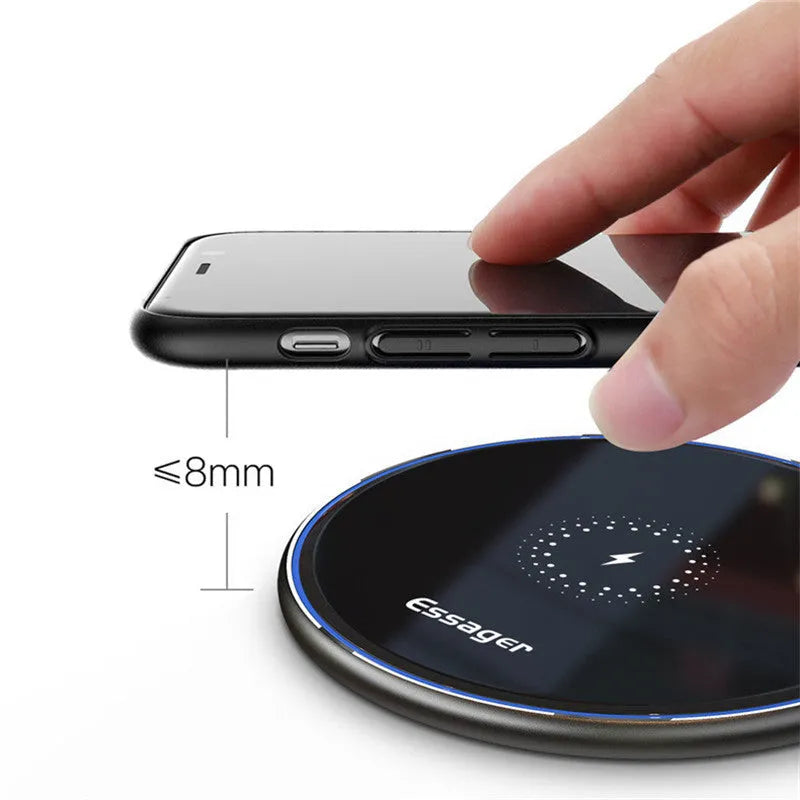 Black aluminium alloy Qi wireless fast charging pad for phones on a wooden desk.