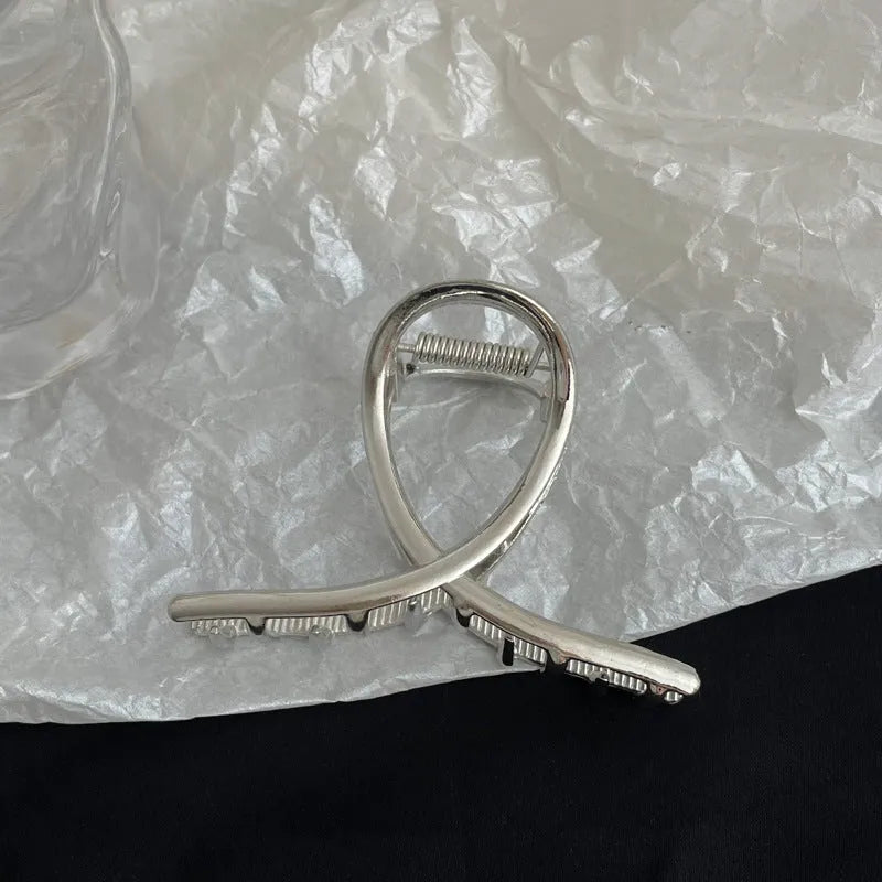 Assortment of silver metal hair claw barrettes with various designs including bows, pearls, and geometric shapes.