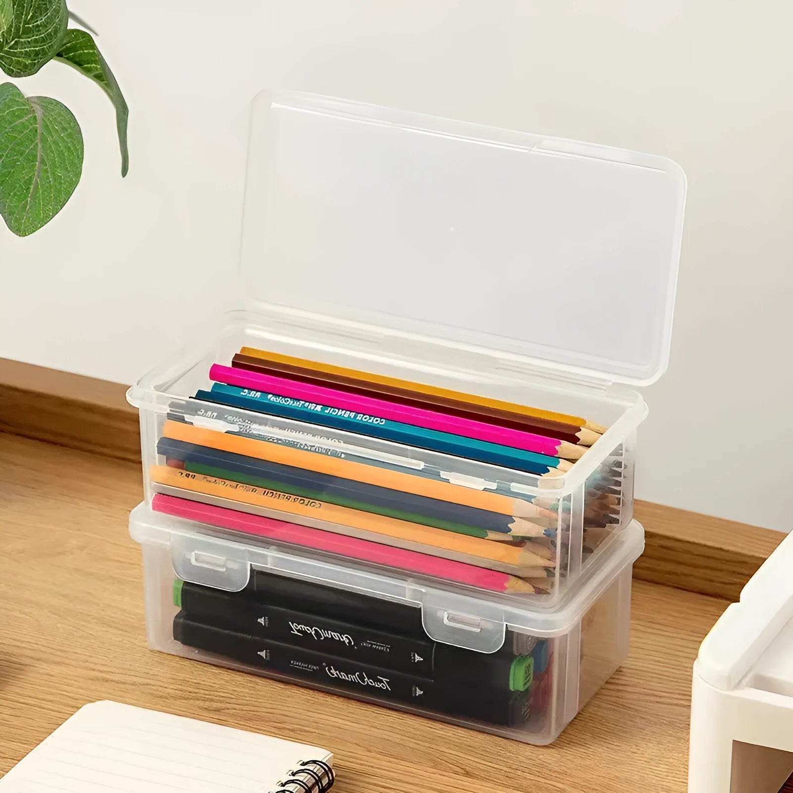 Large clear plastic stationery storage box filled with coloured pencils and wax crayons