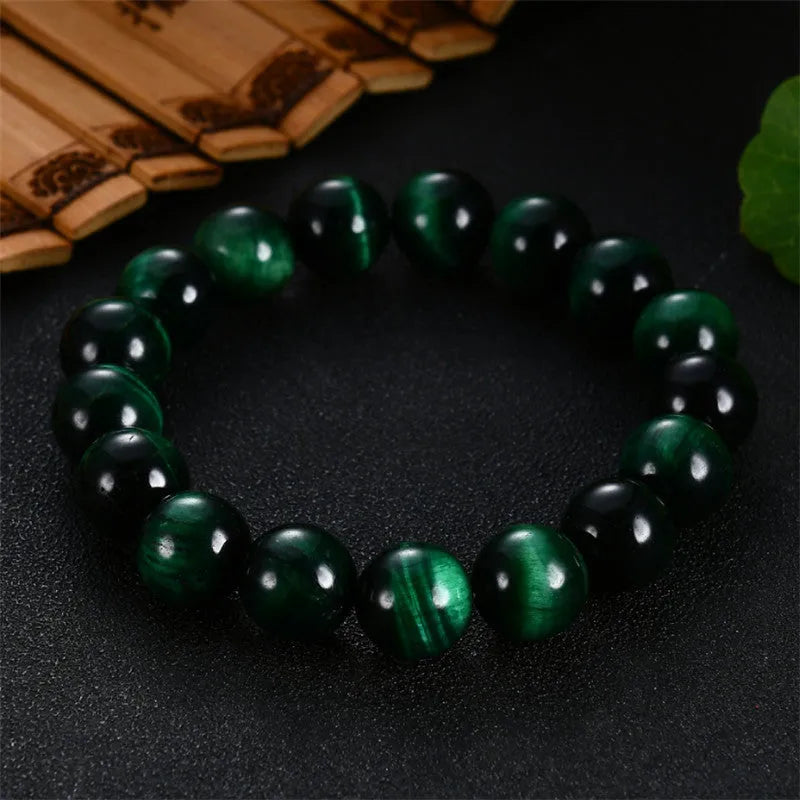 Polished green tiger eye stone bead bracelet on a wrist, showing geometric bead shapes.