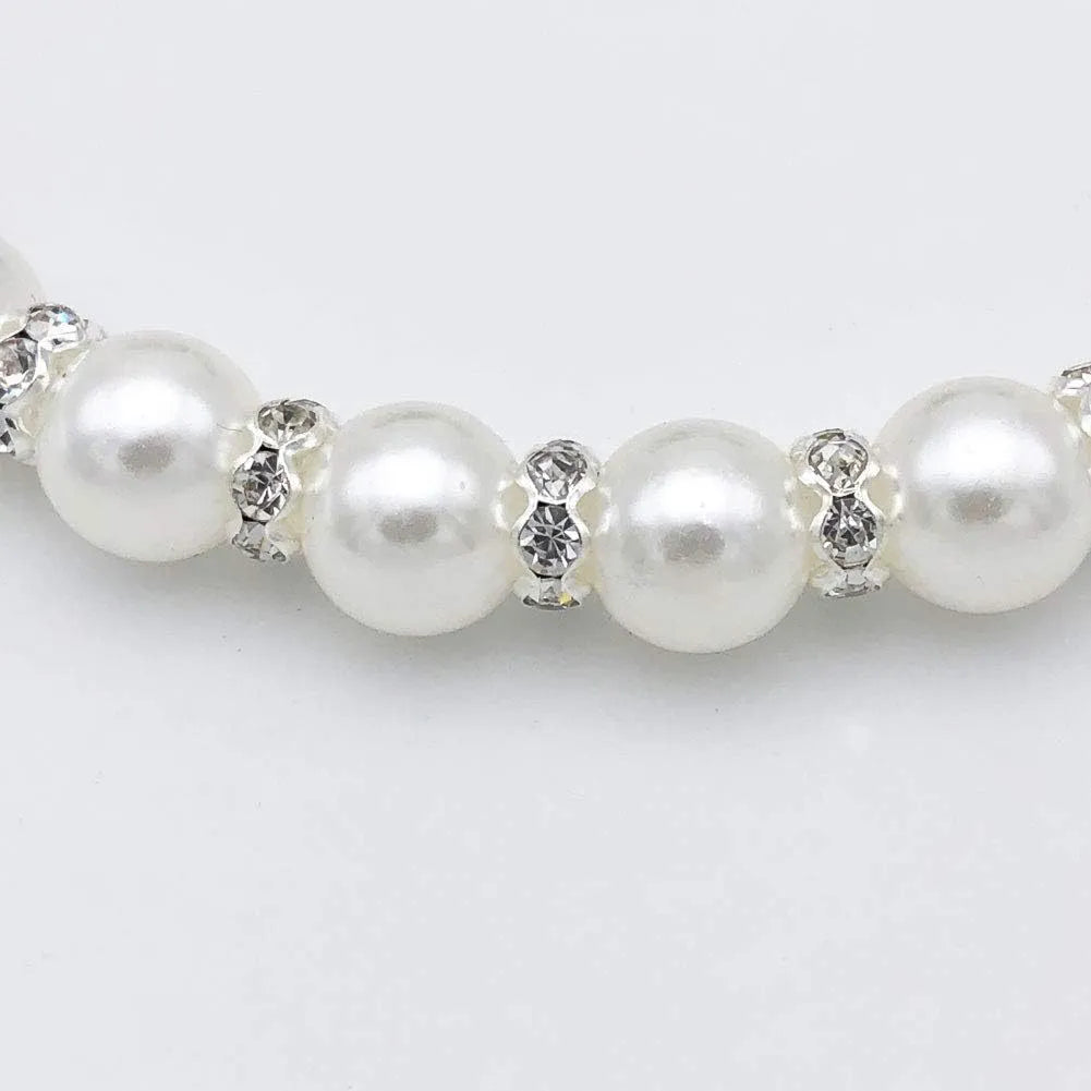 Small dog wearing blue imitation pearl and rhinestone necklace with adjustable clasp and ribbon bow