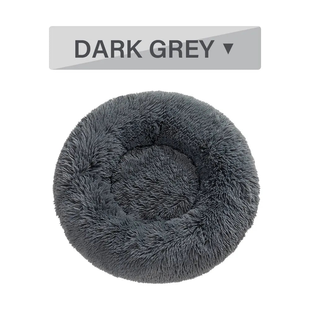 Fluffy donut-shaped dog bed in long plush fabric, shown in a light grey colour with a raised edge.