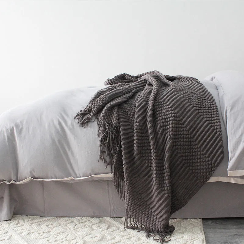 Small dark grey polyester nap blanket folded, showing its size of 127 cm by 170 cm.
