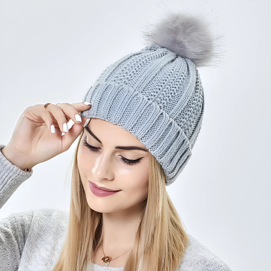 Womens knitted beanie hat with faux fur pom pom, shown in a selection of colours including beige, black, and wine red.